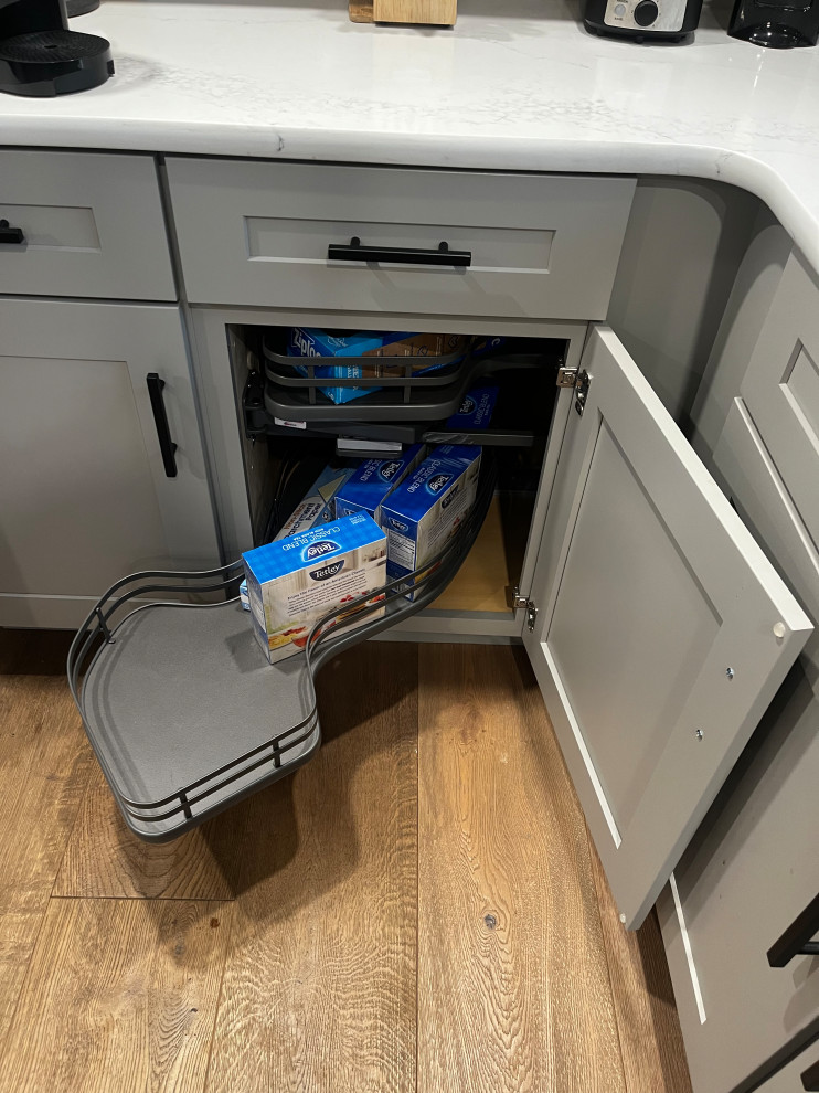 Inspiration for a mid-sized transitional u-shaped light wood floor and brown floor enclosed kitchen remodel in Boston with an undermount sink, shaker cabinets, gray cabinets, quartz countertops, white backsplash, quartz backsplash, stainless steel appliances, a peninsula and white countertops