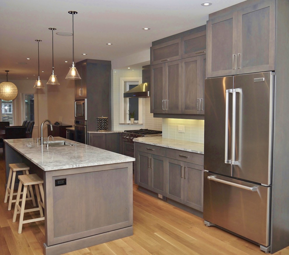 Inspiration for a large contemporary eat-in kitchen in Toronto with an undermount sink, shaker cabinets, grey cabinets, quartzite benchtops, white splashback, glass tile splashback, stainless steel appliances, light hardwood floors and with island.