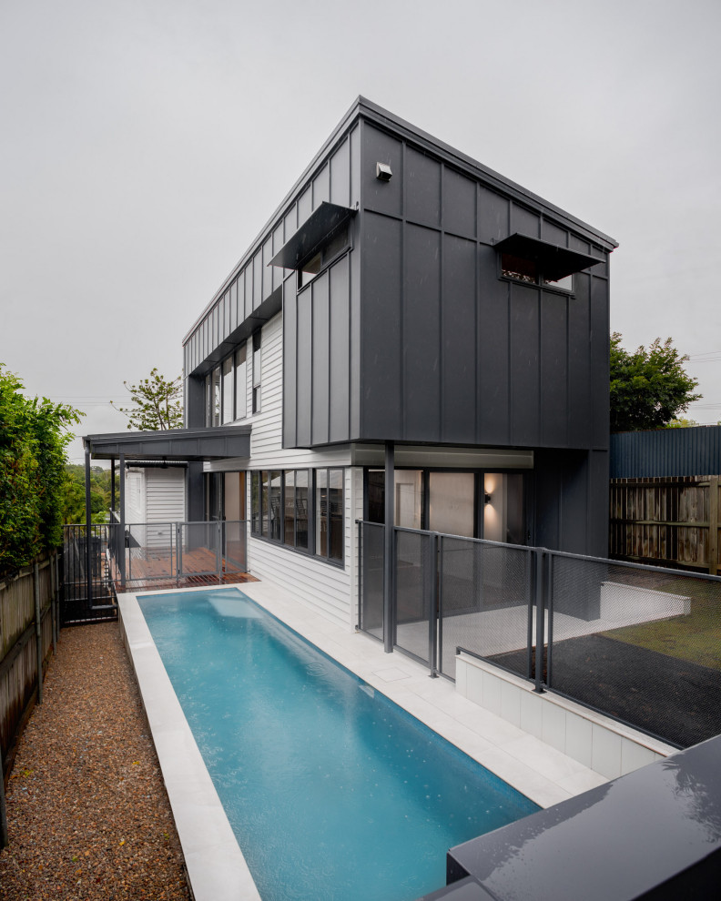 Diseño de fachada de casa azul contemporánea de dos plantas con revestimiento de aglomerado de cemento, tejado de metal y panel y listón