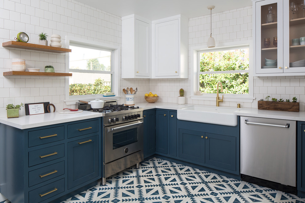 Inspiration for a mid-sized transitional u-shaped kitchen in San Francisco with a farmhouse sink, shaker cabinets, blue cabinets, quartz benchtops, white splashback, ceramic splashback, stainless steel appliances, cement tiles, no island and blue floor.