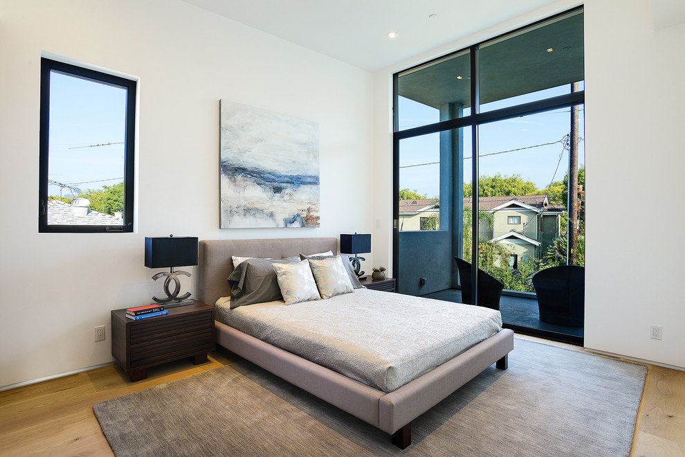 Large contemporary master bedroom in Los Angeles with white walls, light hardwood floors, no fireplace and brown floor.