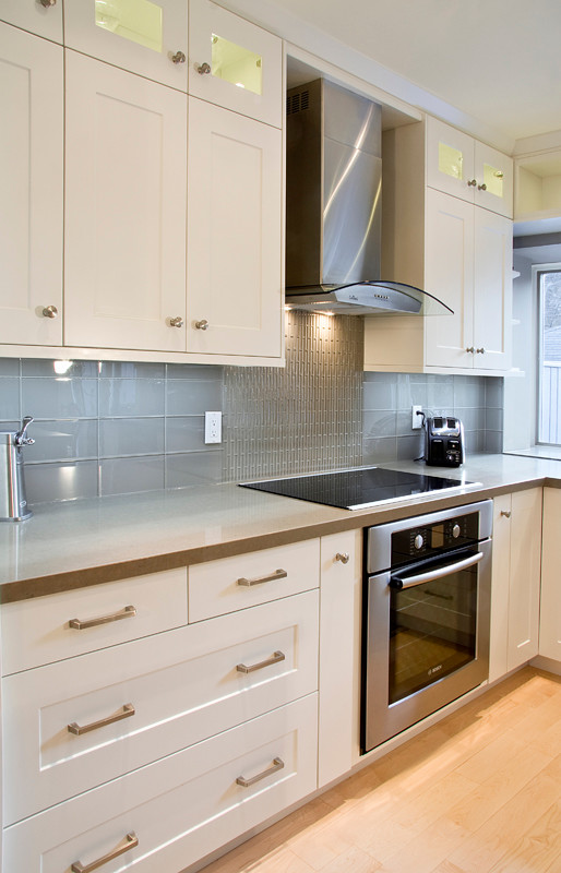 Inspiration for a mid-sized transitional u-shaped eat-in kitchen in Toronto with an undermount sink, shaker cabinets, white cabinets, grey splashback, stainless steel appliances, light hardwood floors, with island and grey benchtop.