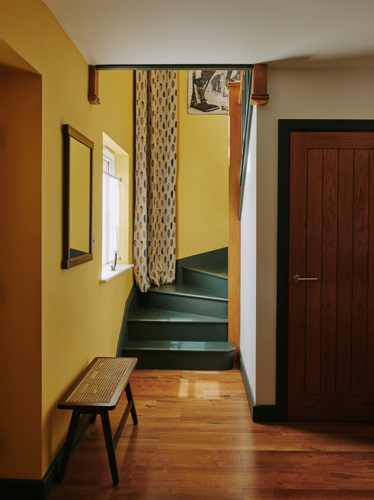 На фото: лестница среднего размера в стиле кантри с крашенными деревянными ступенями, крашенными деревянными подступенками и деревянными перилами