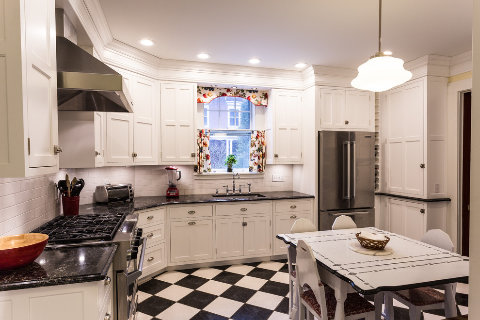 Photo of a mid-sized traditional l-shaped eat-in kitchen in New York with a single-bowl sink, recessed-panel cabinets, white cabinets, laminate benchtops, white splashback, subway tile splashback, white appliances and no island.