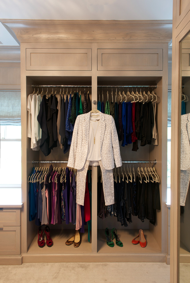 Photo of a mid-sized transitional gender-neutral walk-in wardrobe in New York with shaker cabinets, light wood cabinets and carpet.