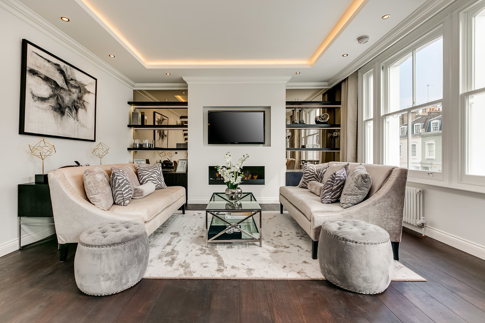This is an example of a transitional living room in London with white walls, medium hardwood floors, a ribbon fireplace, a wall-mounted tv and brown floor.