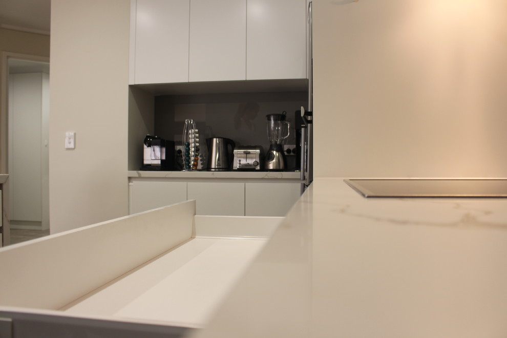 Inspiration for a mid-sized contemporary u-shaped separate kitchen in Melbourne with an undermount sink, flat-panel cabinets, white cabinets, quartz benchtops, brown splashback, glass sheet splashback, stainless steel appliances, light hardwood floors and a peninsula.