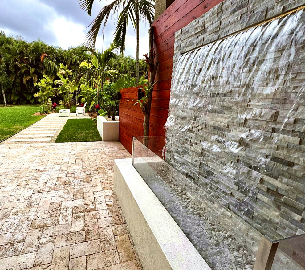 Foto di un piccolo giardino formale moderno esposto in pieno sole dietro casa in estate con un focolare, pavimentazioni in pietra naturale e recinzione in metallo