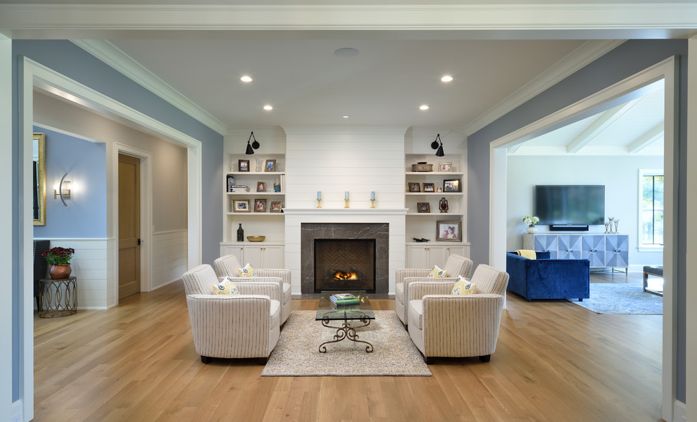 Design ideas for a mid-sized country formal enclosed living room in Chicago with blue walls, light hardwood floors, a standard fireplace, a stone fireplace surround, no tv and brown floor.