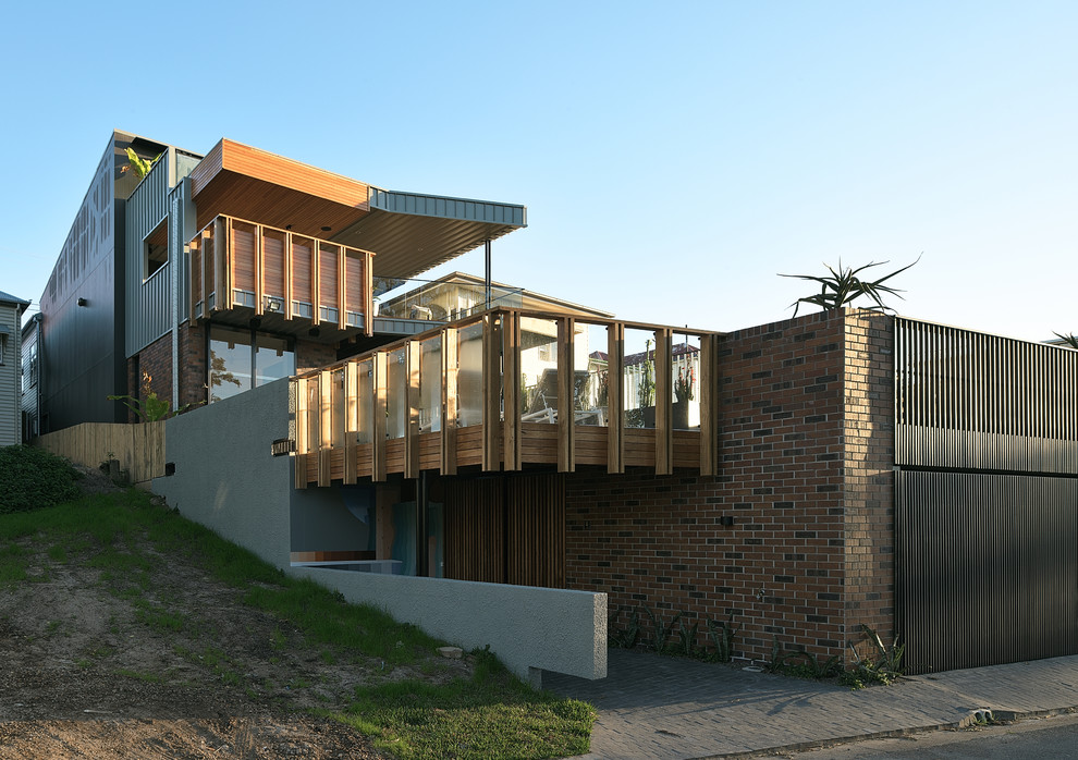 This is an example of a large contemporary three-storey brick house exterior in Brisbane with a metal roof.