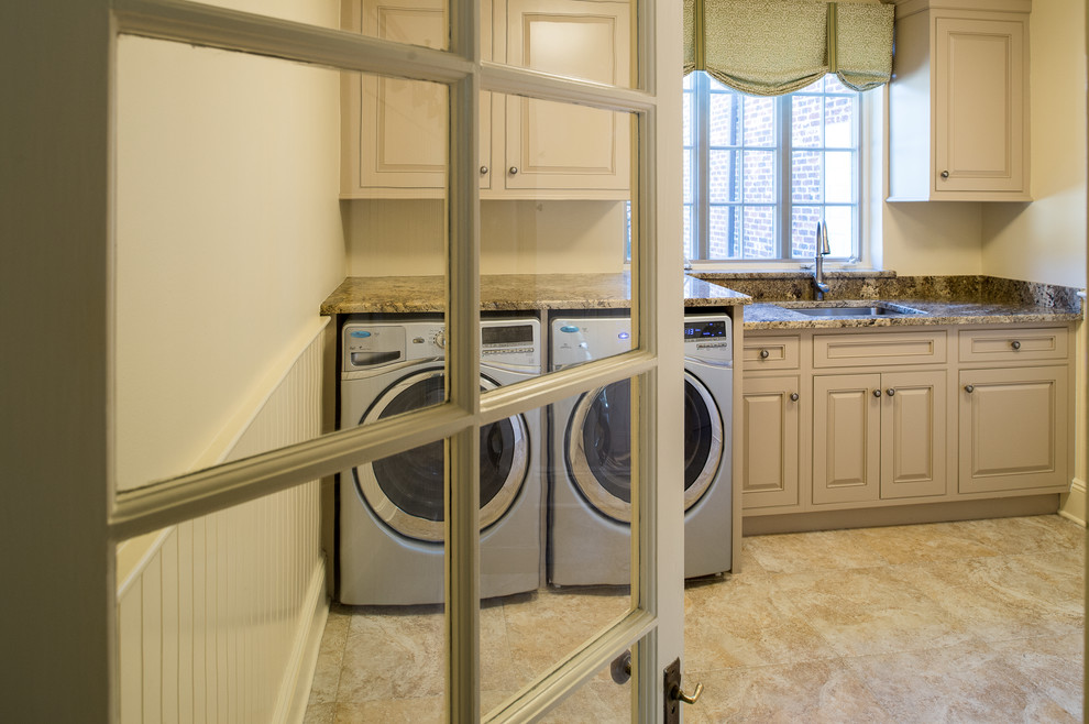 Inspiration for a mid-sized traditional single-wall dedicated laundry room in New York with an undermount sink, raised-panel cabinets, beige cabinets, granite benchtops, beige walls, travertine floors, a side-by-side washer and dryer, brown floor and brown benchtop.