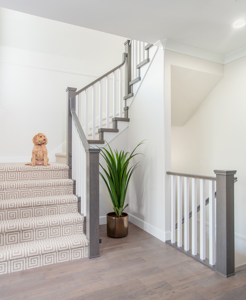 This is an example of a transitional wood u-shaped staircase in Vancouver with wood railing and wood risers.