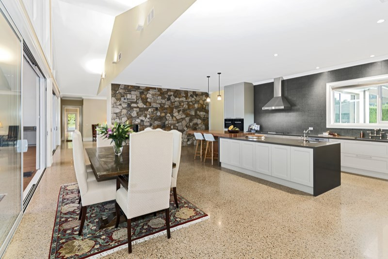 This is an example of an expansive contemporary kitchen in Melbourne with an undermount sink, white cabinets, grey splashback, concrete floors, multiple islands, beige floor and grey benchtop.