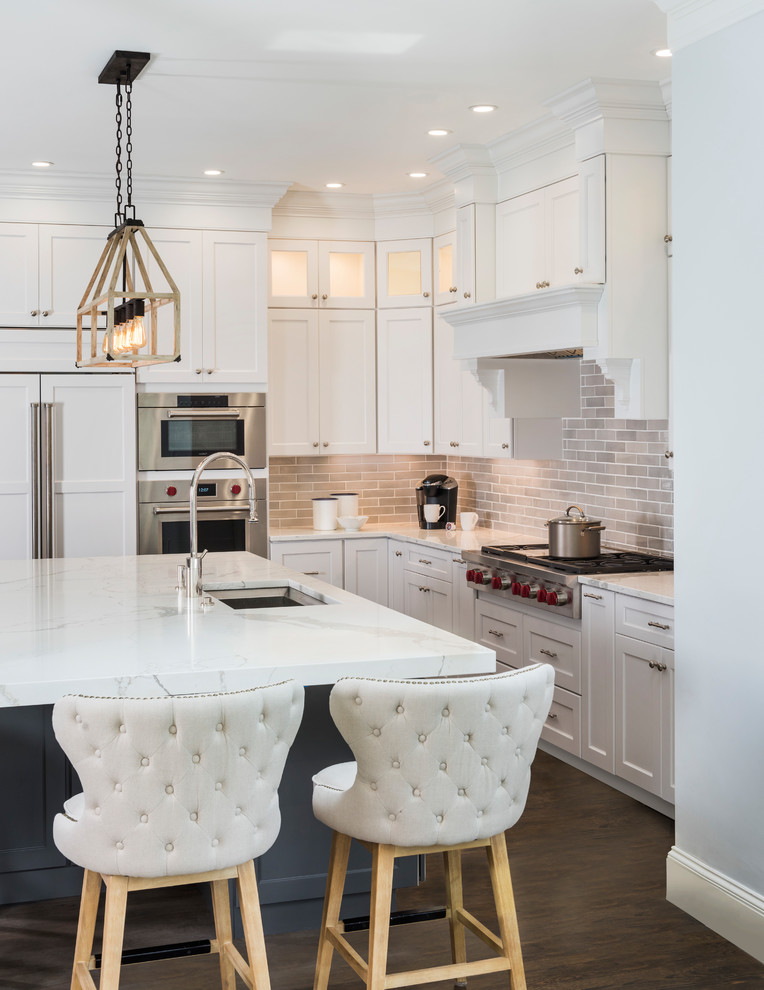 This is an example of a large transitional l-shaped eat-in kitchen in Boston with an undermount sink, recessed-panel cabinets, white cabinets, marble benchtops, grey splashback, ceramic splashback, stainless steel appliances, medium hardwood floors, with island and brown floor.