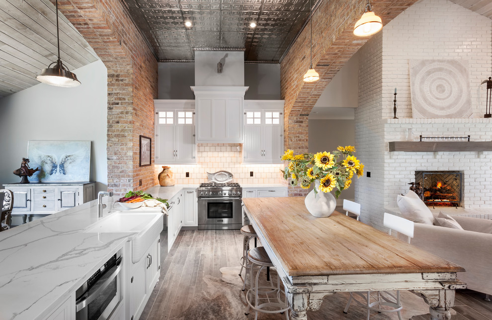 Open concept kitchen - mid-sized shabby-chic style l-shaped ceramic tile and gray floor open concept kitchen idea in Detroit with a farmhouse sink, shaker cabinets, white cabinets, quartz countertops, beige backsplash, mosaic tile backsplash, stainless steel appliances and an island