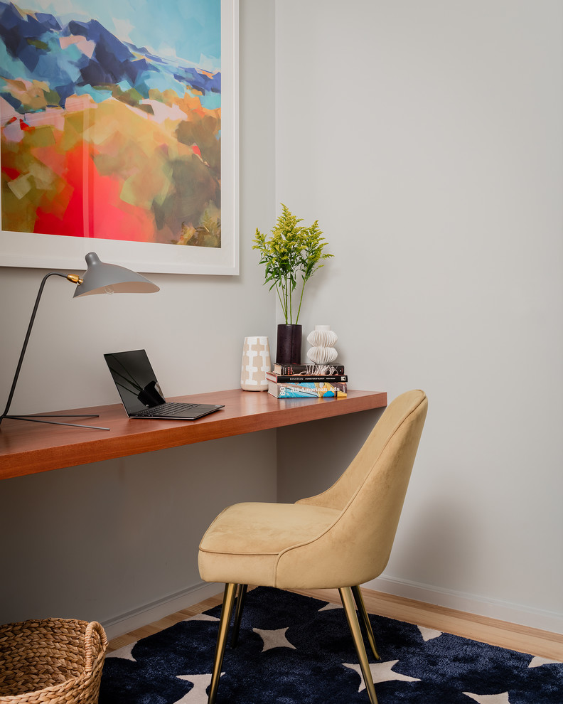 This is an example of a small beach style study room in Boston with grey walls, light hardwood floors and a built-in desk.