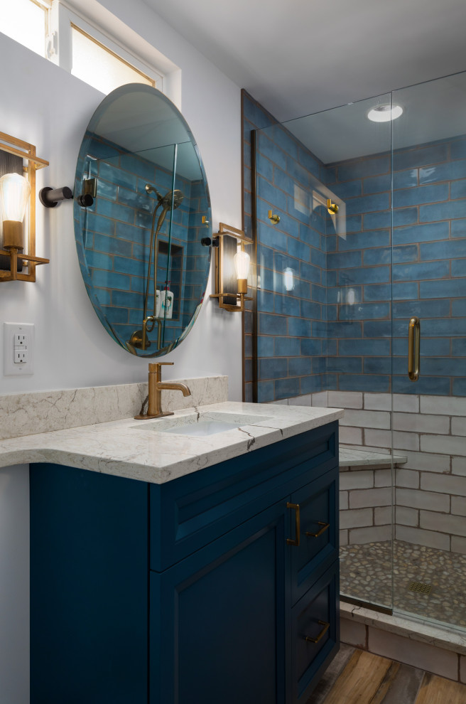 Photo of a mid-sized transitional 3/4 bathroom in Denver with furniture-like cabinets, blue cabinets, an alcove shower, a two-piece toilet, blue tile, ceramic tile, blue walls, wood-look tile, an undermount sink, engineered quartz benchtops, beige floor, a hinged shower door, a shower seat, a single vanity and a freestanding vanity.