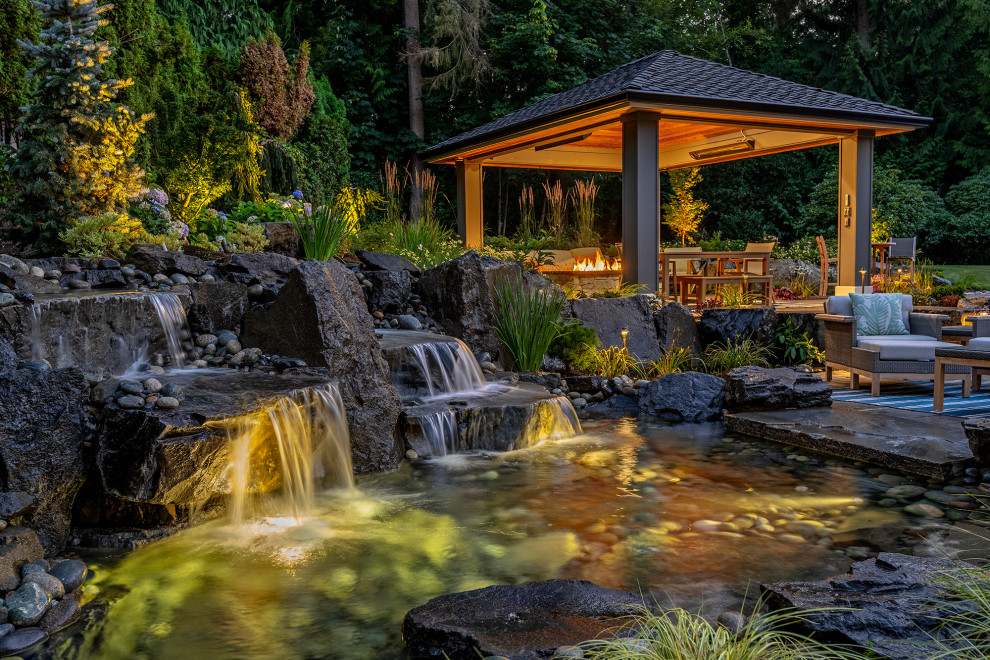 Exemple d'un grand jardin arrière craftsman avec une cascade et des pavés en pierre naturelle.