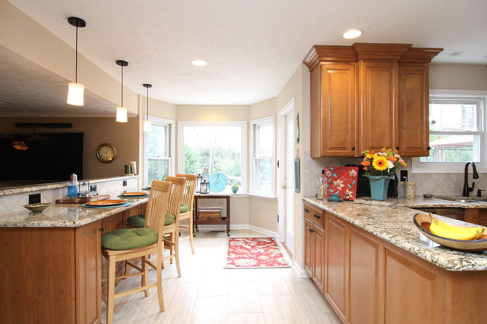 Inspiration for a mid-sized transitional u-shaped porcelain tile eat-in kitchen remodel with an undermount sink, raised-panel cabinets, medium tone wood cabinets, granite countertops, beige backsplash, porcelain backsplash and stainless steel appliances