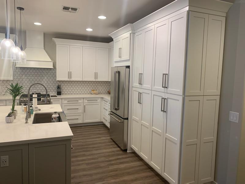Inspiration for a mid-sized transitional u-shaped laminate floor eat-in kitchen remodel in Phoenix with a farmhouse sink, shaker cabinets, white cabinets, quartz countertops, gray backsplash, porcelain backsplash, stainless steel appliances, an island and white countertops