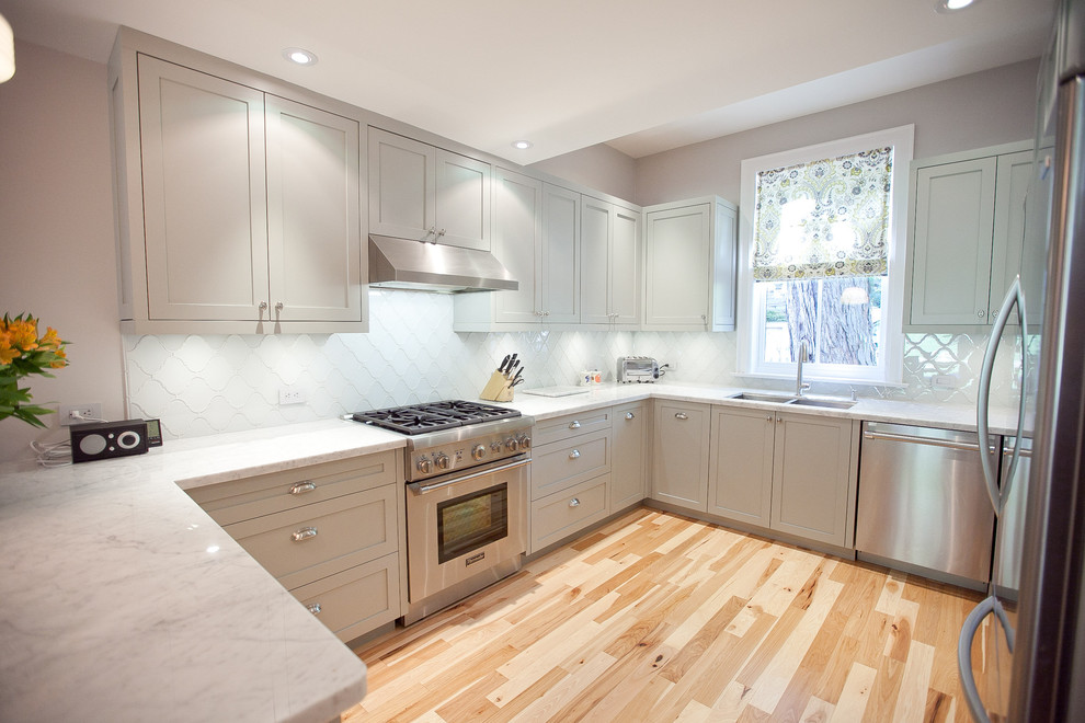 Inspiration for a transitional u-shaped kitchen in Toronto with a double-bowl sink, shaker cabinets, grey cabinets, marble benchtops, white splashback and stainless steel appliances.