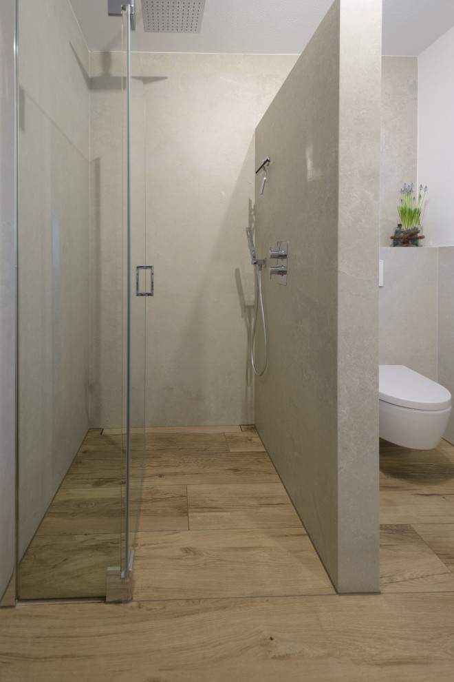 Exempel på ett modernt badrum, med släta luckor, vita skåp, en kantlös dusch, grå kakel och brunt golv