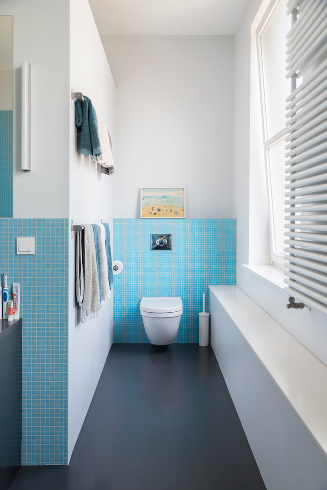 This is an example of a contemporary bathroom in Berlin with a wall-mount toilet, blue tile, mosaic tile and white walls.