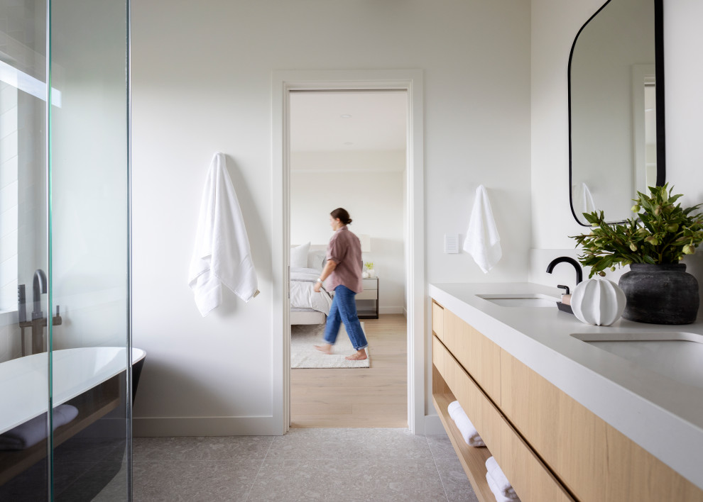 Inspiration for a mid-sized contemporary master bathroom in Vancouver with flat-panel cabinets, light wood cabinets, a freestanding tub, a corner shower, white walls, an undermount sink, a hinged shower door, grey benchtops, a shower seat, a double vanity and a built-in vanity.