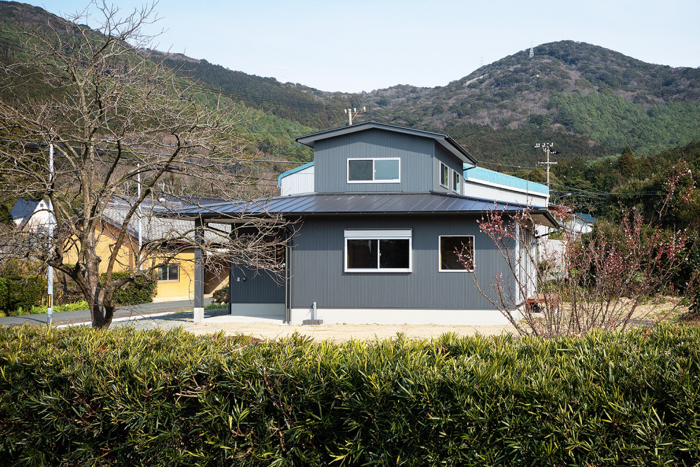 Inspiration pour une petite façade de maison métallique et grise asiatique en planches et couvre-joints à un étage avec un toit à deux pans, un toit en métal et un toit noir.
