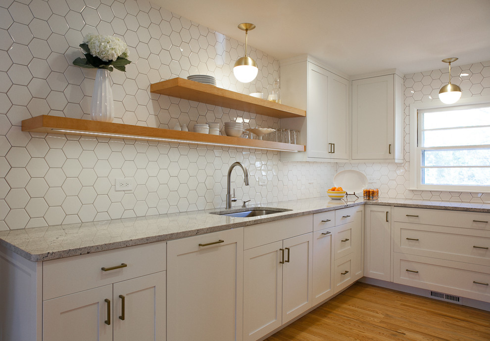 Photo of a small transitional u-shaped eat-in kitchen in Atlanta with an undermount sink, shaker cabinets, white cabinets, granite benchtops, white splashback, ceramic splashback, stainless steel appliances, light hardwood floors and no island.