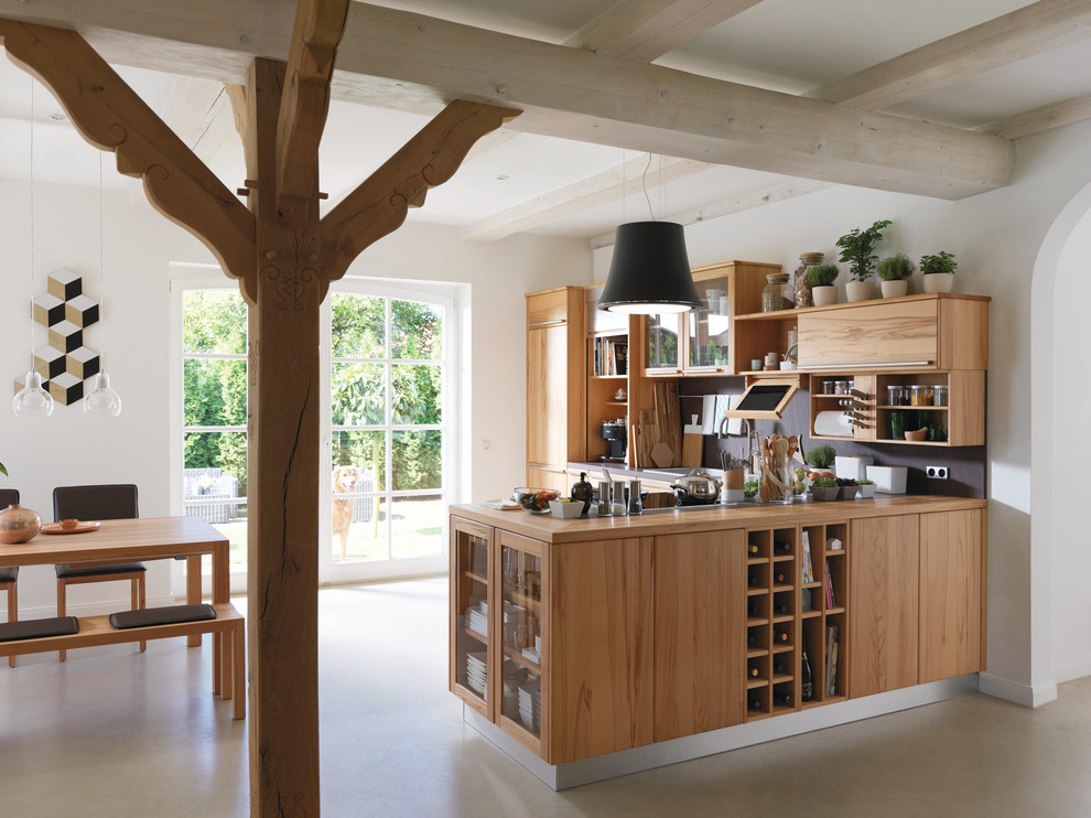 Photo of a mid-sized country l-shaped open plan kitchen in Hanover with flat-panel cabinets, medium wood cabinets, wood benchtops, black splashback, vinyl floors, a peninsula and beige floor.