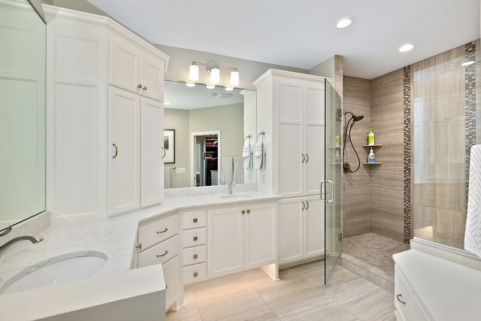 This is an example of a large transitional 3/4 bathroom in Minneapolis with recessed-panel cabinets, white cabinets, an alcove shower, a two-piece toilet, brown tile, porcelain tile, grey walls, porcelain floors, an undermount sink, marble benchtops, beige floor, a hinged shower door and grey benchtops.
