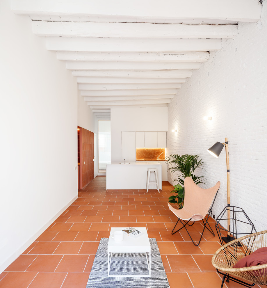 This is an example of a mediterranean open concept living room in Barcelona with white walls, terra-cotta floors and orange floor.