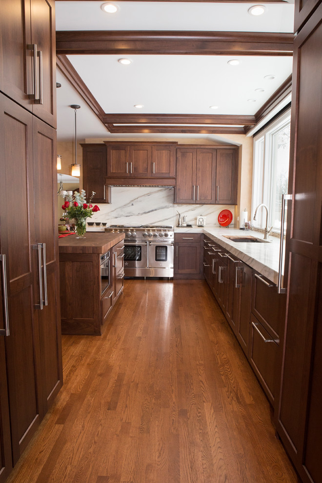 Inspiration for an expansive transitional u-shaped eat-in kitchen in Chicago with an undermount sink, dark wood cabinets, marble benchtops, white splashback, matchstick tile splashback, stainless steel appliances, medium hardwood floors, with island and recessed-panel cabinets.
