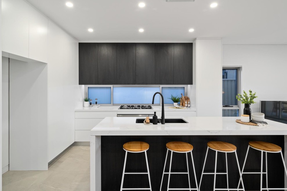 Mid-sized modern l-shaped separate kitchen in Sydney with a double-bowl sink, flat-panel cabinets, white cabinets, marble benchtops, blue splashback, glass sheet splashback, stainless steel appliances, marble floors, with island, brown floor and white benchtop.