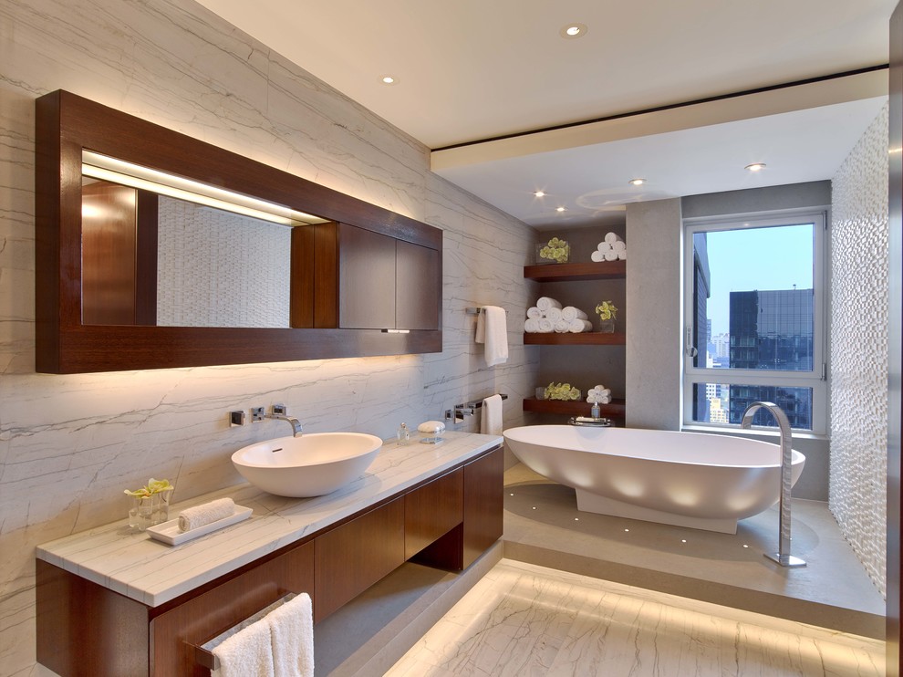 This is an example of a contemporary master bathroom in New York with a vessel sink, flat-panel cabinets, medium wood cabinets, marble benchtops, white tile, stone slab, white walls and marble floors.
