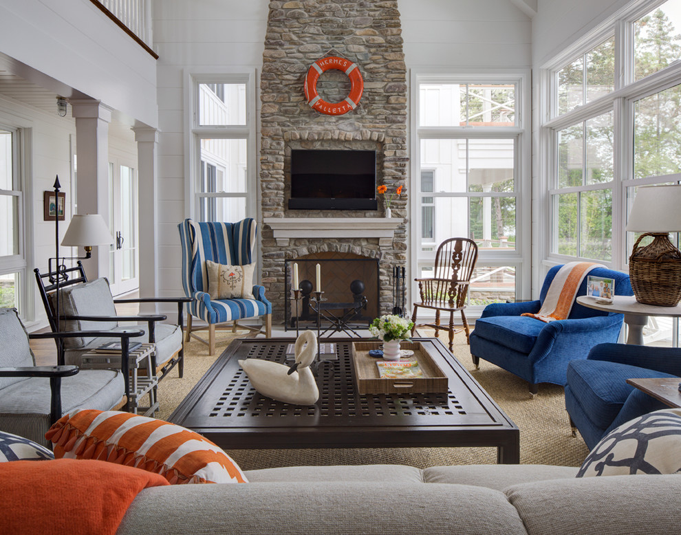 This is an example of a beach style formal living room in Milwaukee with white walls, medium hardwood floors, a standard fireplace, a stone fireplace surround and a wall-mounted tv.