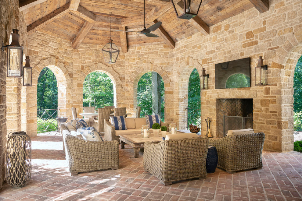 Design ideas for a large rustic back patio in New Orleans with a fireplace, brick paving and a roof extension.