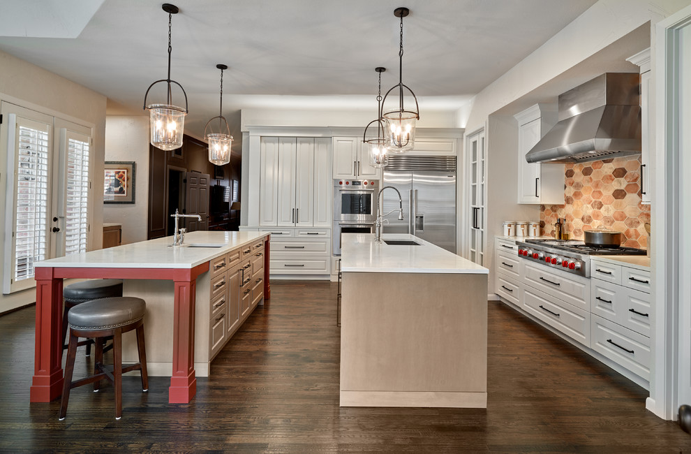 Design ideas for a large traditional kitchen in Dallas with a farmhouse sink, raised-panel cabinets, red cabinets, quartz benchtops, multi-coloured splashback, cement tile splashback, stainless steel appliances, medium hardwood floors, multiple islands, brown floor and white benchtop.