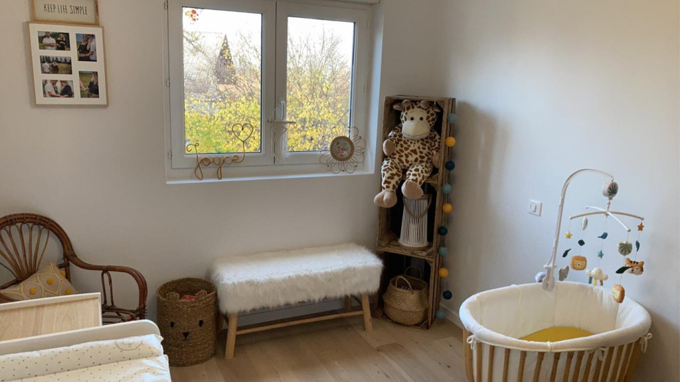 Foto på ett mellanstort minimalistiskt könsneutralt babyrum, med vita väggar, ljust trägolv och beiget golv