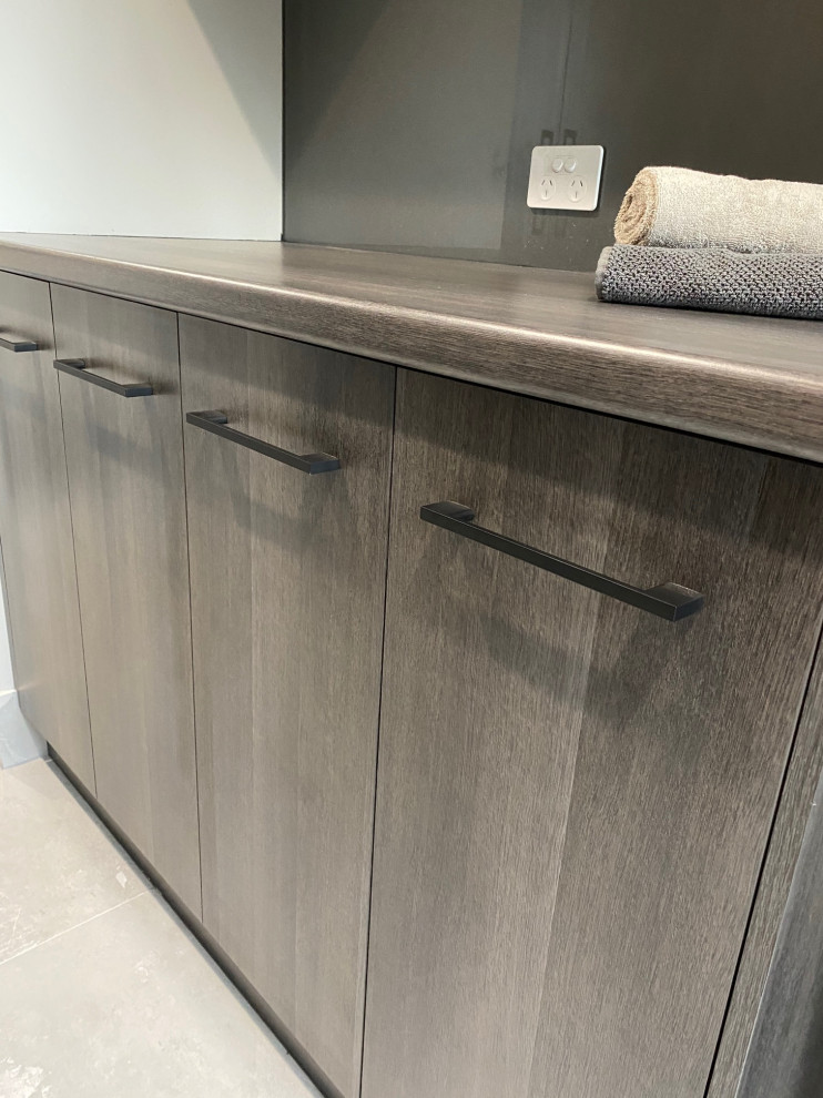 This is an example of a large contemporary galley dedicated laundry room in Adelaide with grey cabinets, laminate benchtops, white walls and grey benchtop.