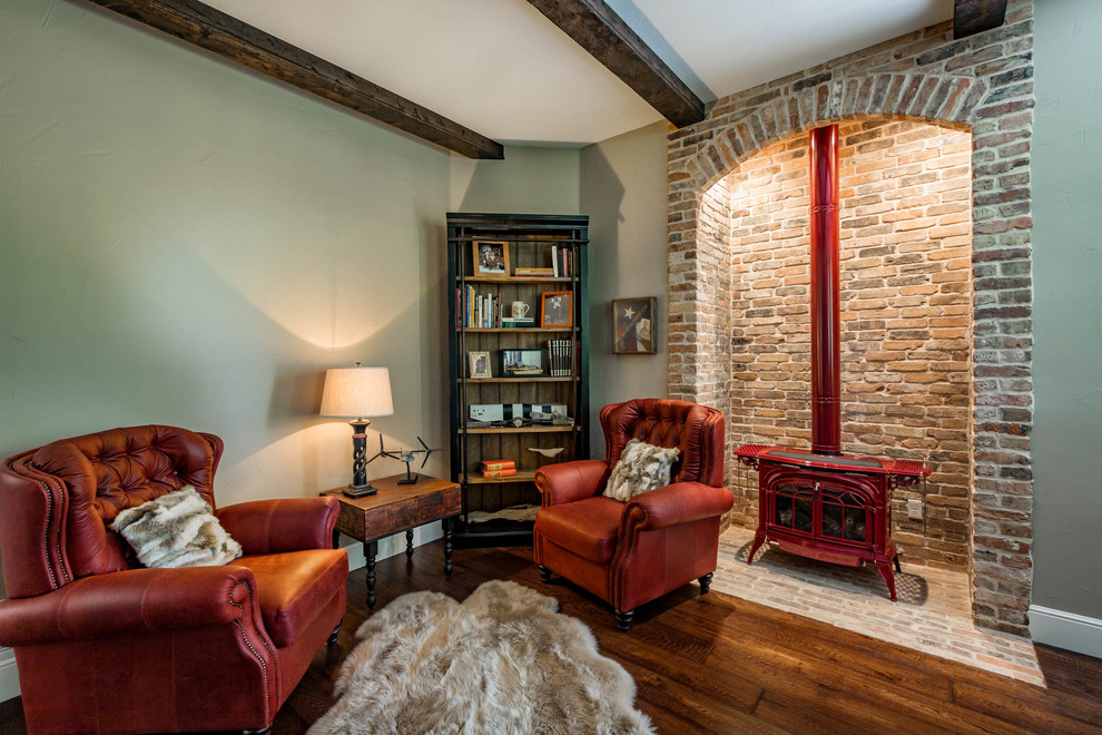 This is an example of a country home office in Dallas with a library, green walls, medium hardwood floors, a standard fireplace, a brick fireplace surround and brown floor.