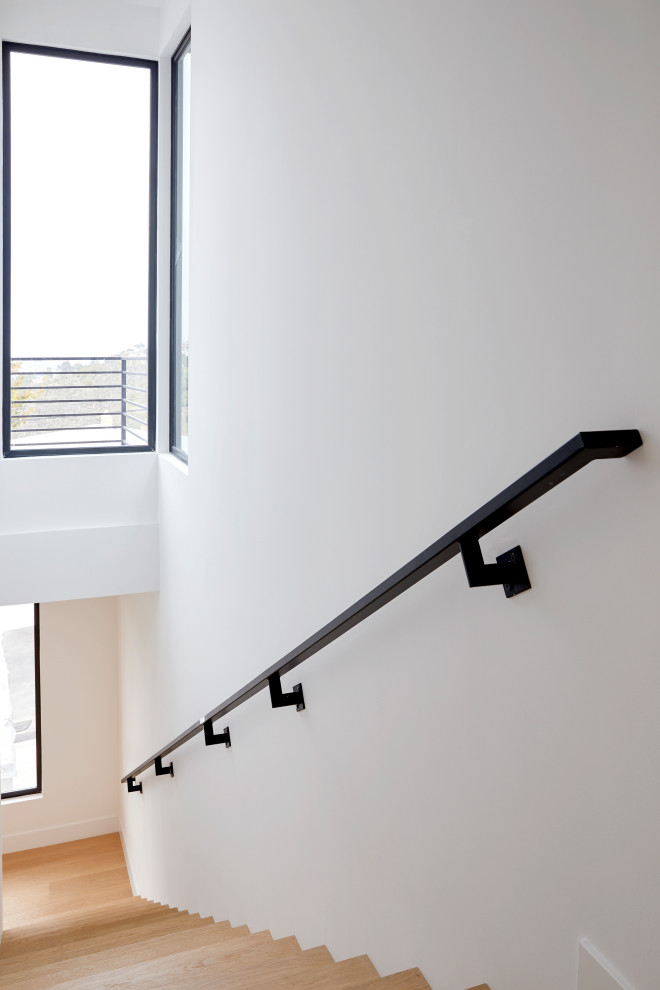 Foto de escalera recta minimalista de tamaño medio con escalones de madera, contrahuellas de madera y barandilla de metal