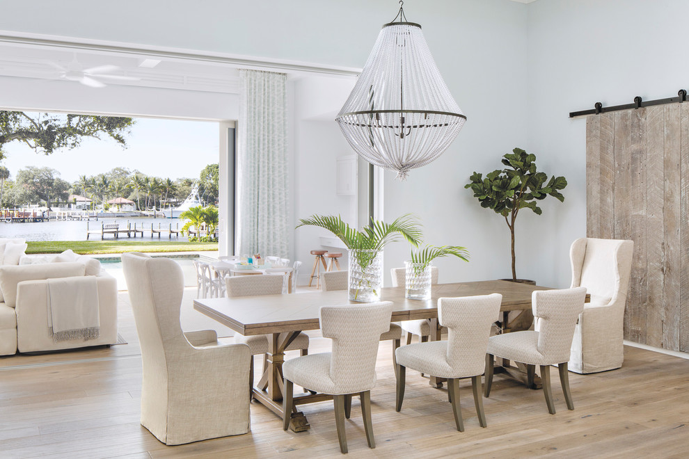 This is an example of a beach style open plan dining in Miami with white walls, light hardwood floors and beige floor.
