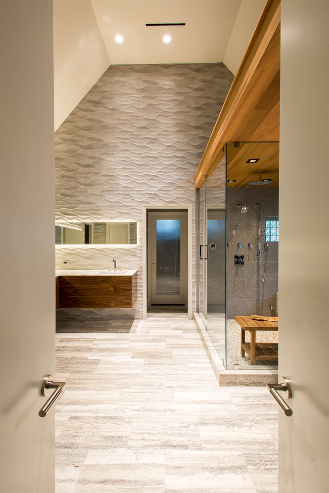 This is an example of a large contemporary bathroom in Dallas with flat-panel cabinets, medium wood cabinets, a drop-in tub, a one-piece toilet, gray tile, porcelain tile, grey walls, marble floors, an undermount sink, marble benchtops and with a sauna.
