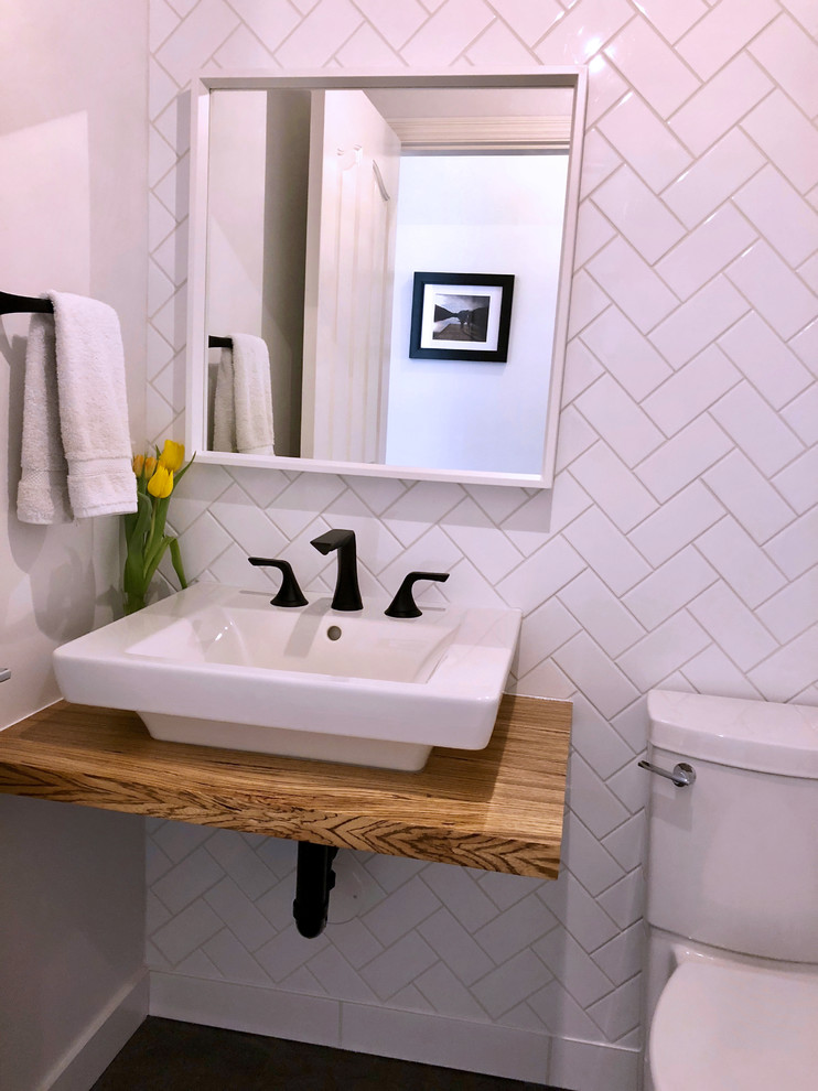Inspiration for a small contemporary powder room in Vancouver with a two-piece toilet, white tile, white walls, a wall-mount sink, wood benchtops and subway tile.