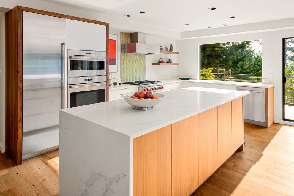 Mid-sized midcentury u-shaped eat-in kitchen in Vancouver with an undermount sink, flat-panel cabinets, white cabinets, quartz benchtops, green splashback, glass tile splashback, stainless steel appliances, light hardwood floors, with island, beige floor and white benchtop.