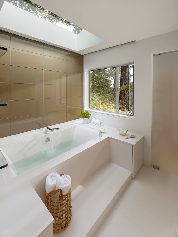 This is an example of a large contemporary master bathroom in San Francisco with an alcove tub, white tile, stone slab, white walls, porcelain floors, flat-panel cabinets, white cabinets, an undermount sink and solid surface benchtops.