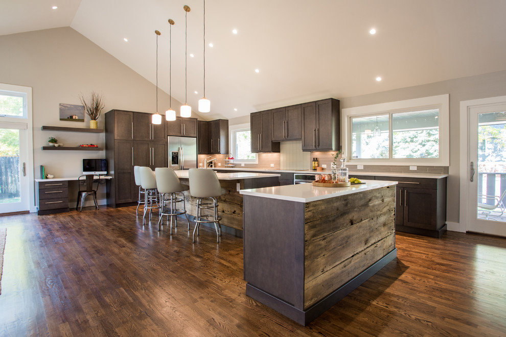 Transitional kitchen in Denver with recessed-panel cabinets, dark wood cabinets, stainless steel appliances, dark hardwood floors and multiple islands.