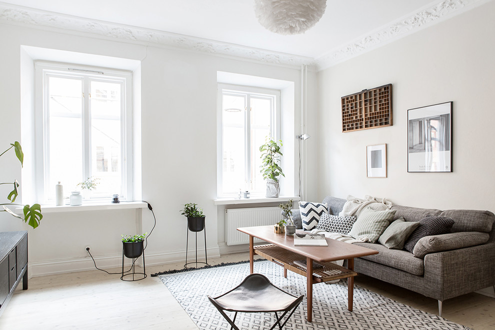 This is an example of a mid-sized scandinavian enclosed living room in Gothenburg with white walls, light hardwood floors, no fireplace and no tv.